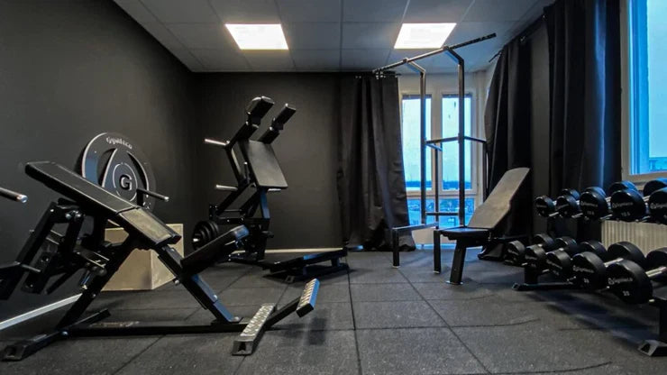 Firmenfitnessraum bei Better Bodies mit Plate-Loaded-Geräten, Trainingsbänken und Kurzhantelablage