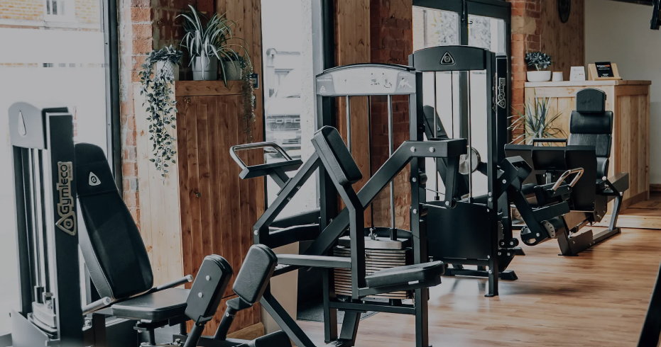 Gerätebereich des Boutique-Studios EmpowHER mit Gymleco Steckgewicht-Maschinen vor Ziegelwand